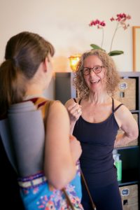 Carol Gray is talking with a pregnant student after a prenatal yoga class.